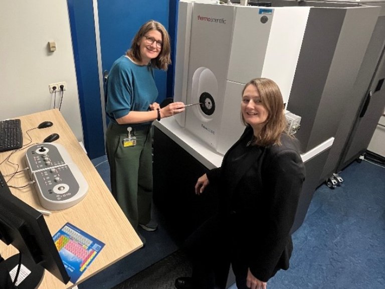 Left: Dr. Nicole van der Wel and right: Dr. Katy Wolstencroft, standing next to one of the current microscopes.