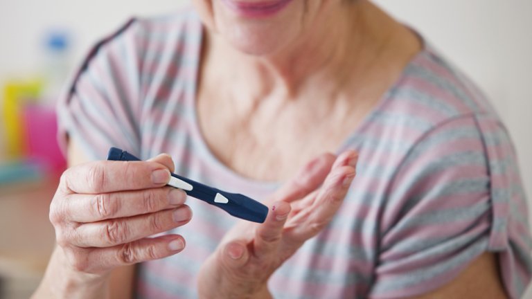 Older woman testing blood for diabetes