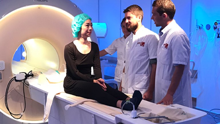 Onderzoekers Matthias Cabri en Onno Baur (r) overleggen met Ani Liu kort voordat ze de MRI in gaat.